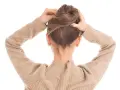 Manos arreglando un moño alto despeinado, perfecto para una boda.