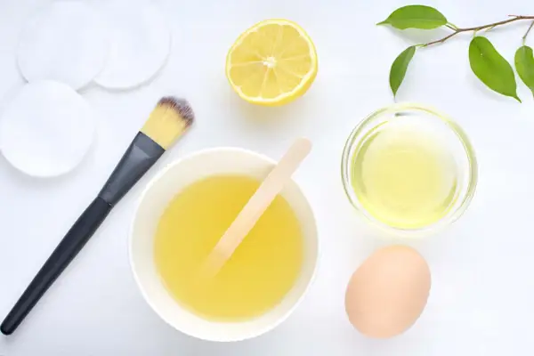 Ingredientes para una mascarilla casera para el pelo: limón, huevo, aceite y aplicador.